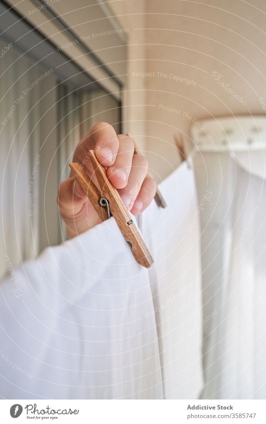 Nicht erkennbare Person, die mit Heringen am Seil hängende Kleidung auf dem Balkon Wäscherei Kleiderspin Leinen nass trocknen Sonnenlicht Sommer heimisch Arbeit