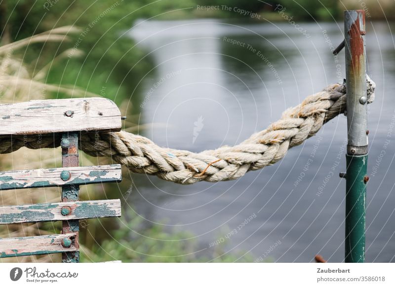 Geflochtenes Tau an einer alten Bank und Eisenstange am Ufer der Havel geflochten Flechtwerk Stange Fluss Wasser grün abgeplatzt verwittert Ruhe beschaulich