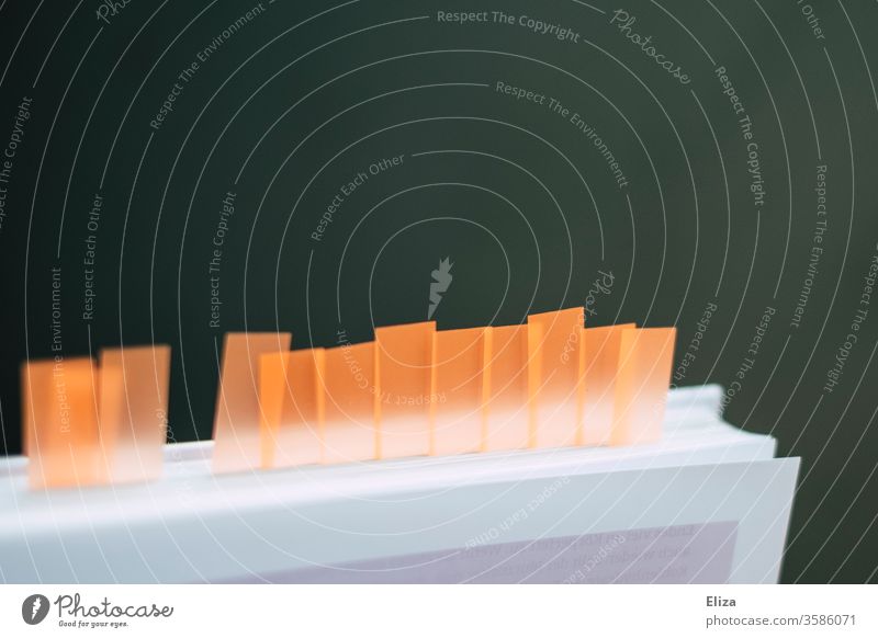 Ein Buch mit vielen Haftmarkern und Sticky Notes um Seiten zu markieren Page Marker markierungen Lesezeichen lernen Notizen Unterlagen Studium orange lesen