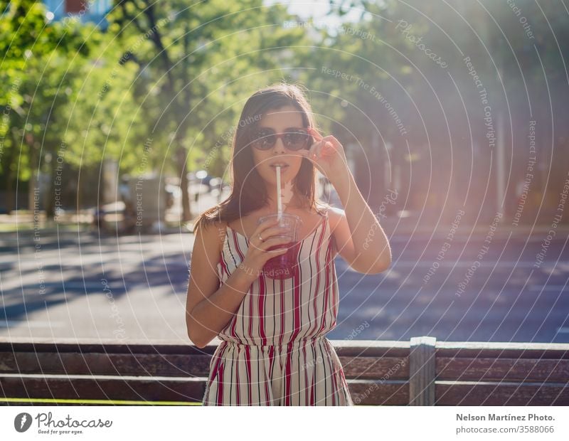 Süße Frau auf der Straße. Sie trinkt im Sommer einen kalten Tee. Sie trägt eine Sonnenbrille. im Freien Mädchen Menschen jung trinken Wellness aktiv blau