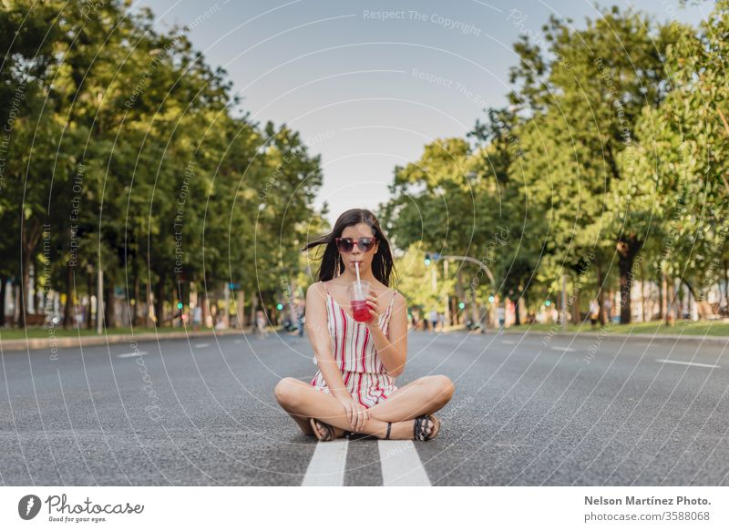 Süße Frau auf der Straße. Sie trinkt im Sommer einen kalten Tee. Sie trägt eine Sonnenbrille. im Freien Mädchen Menschen jung trinken Wellness aktiv blau