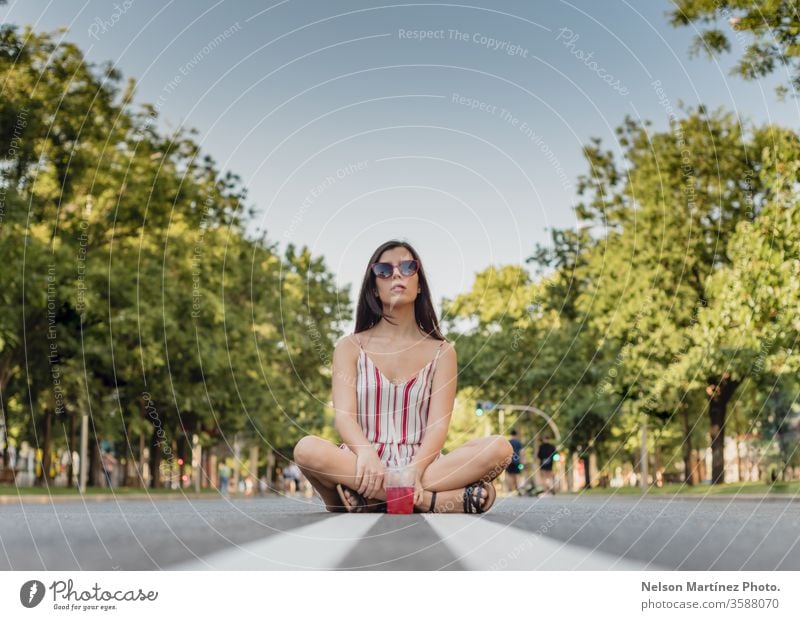 Süße Frau auf der Straße. Sie trinkt im Sommer einen kalten Tee. Sie trägt eine Sonnenbrille. im Freien Mädchen Menschen jung trinken Wellness aktiv blau