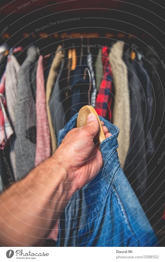 ein blaues Hemd aus dem Kleiderschrank Hand Kleidung anziehen Kleiderständer greifen Entscheidung Bekleidung Mode Innenaufnahme Stil hängen Kleiderbügel