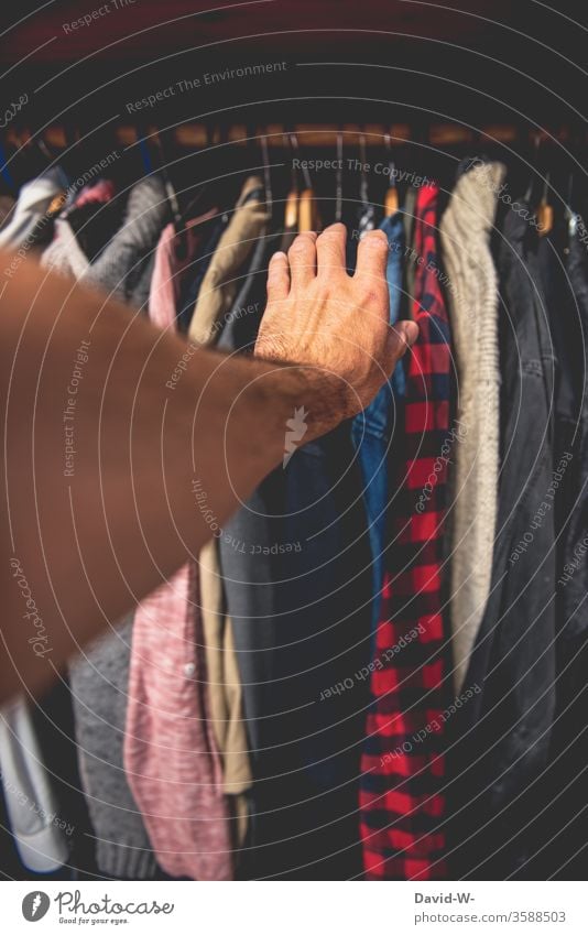 Griff in den Kleiderschrank Hand Kleidung anziehen Kleiderständer Hemd greifen Entscheidung Bekleidung Mode Innenaufnahme Stil hängen Kleiderbügel Farbfoto