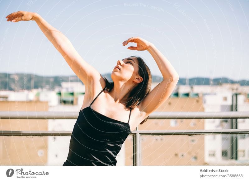 Gelassene Frau tanzt auf der Terrasse Tanzen Anmut Tänzer Gelassenheit ausführen Sommer ruhig beweglich Handfläche Baum urban jung aufschauend Windstille