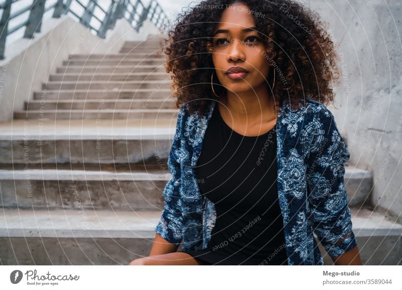 Afroamerikanische Frau, die auf Stufen sitzt. Afro-Look grau jung Mädchen Gesicht Wand Ausdruck Erwachsener Blick Mode schwarz Stehen Lächeln selbstbewusst