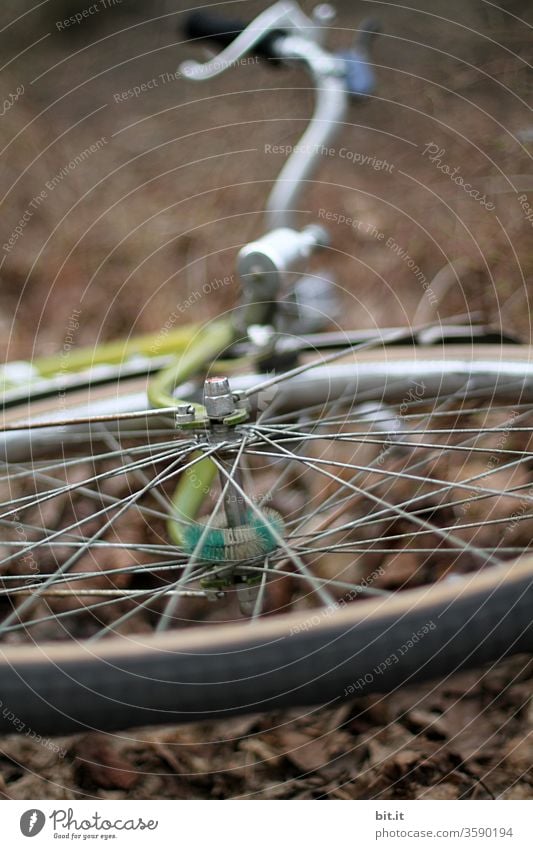 Vorderreifen, Radnarbe, Lenker, Dynamo vom Fahrrad von unten mit schwacher Tiefenschärfe. Gestohlenes, geklautes Rad liegt liegen gelassen auf dem braunen herbstlichen Boden. Umgefallenes Rad, nach Unfall, Sturz, Umkippen auf der Seite liegend im Herbst.