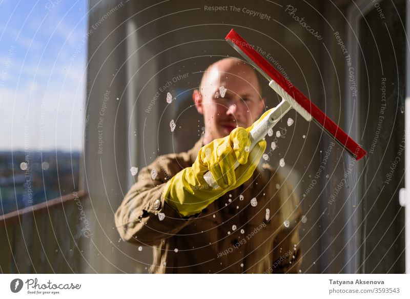 Mann wäscht Fenster in gelben Gummihandschuhen Raumpfleger Sauberkeit heimisch Arbeit Glas Rakel Hausarbeit Waschen Wasser Person Hygiene heimwärts durchsichtig