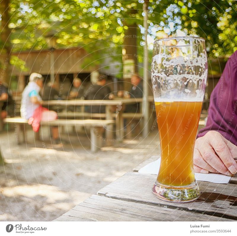 Glas bayrisches Bier im Biergarten, verschwommener Hintergrund typisch bayerisch trinken Bierschaum unter freiem Himmel saisonbedingt Restaurant