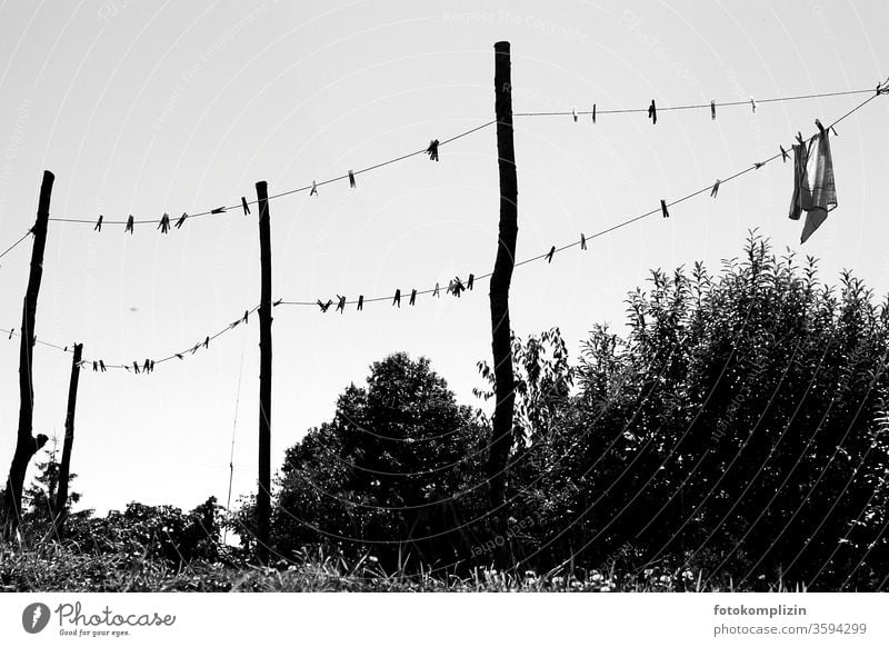 Wäscheleine mit Wäscheklammern und Pfosten als  schwarz weisse Silhouette gegen Himmel Waschtag trocknen Sauberkeit Haushalt Alltagsfotografie hängen aufhängen