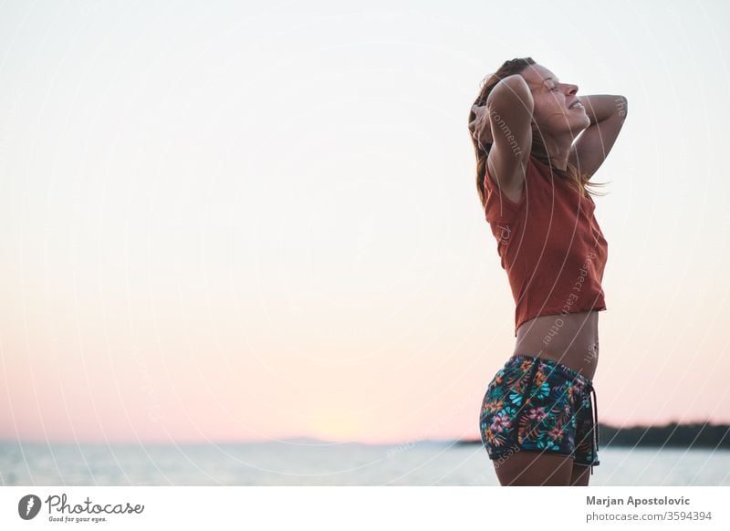 Junge Frau genießt Sonnenuntergang am Strand lässig Glück Lifestyle Sonnenaufgang MEER Meer Wasser reisen Urlaub genießend Feiertag Sommer Freiheit im Freien