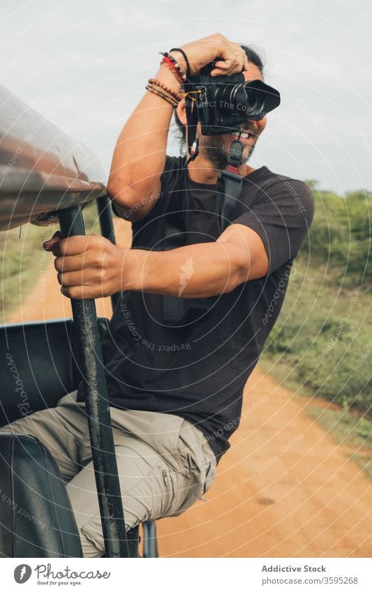 Inhalt männlicher Reisender beim Fotografieren von Landschaftsbildern Safari Mann fotografieren heiter malerisch Natur Urlaub ethnisch reisen Ausflug sitzen PKW