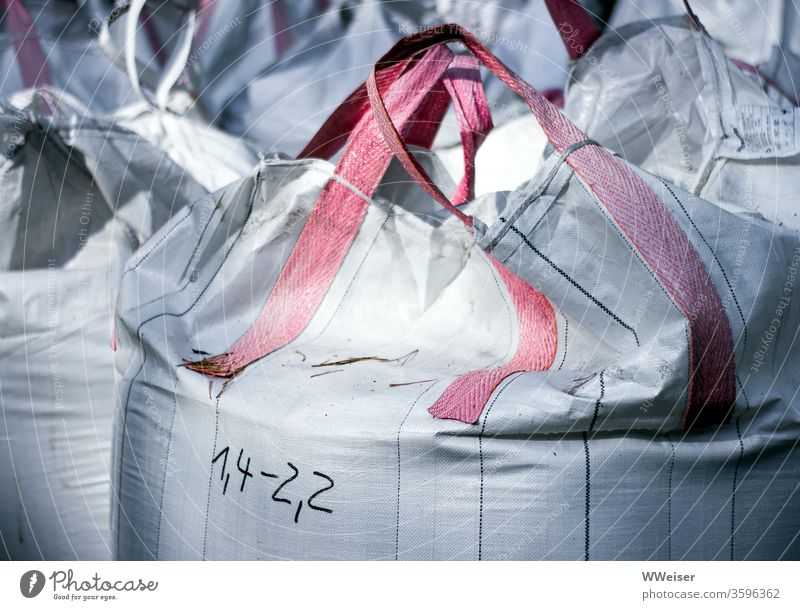 Weiße Säcke auf einer Baustelle Sack Sandsack voll Tragetasche Tragegriffe schwer Zahlen Angabe Gewicht bauen Baumaterial weiß