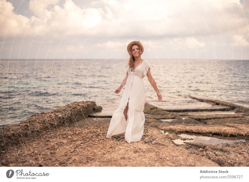 Zufriedene Frau in Kleid und Hut am Meer sorgenfrei reisen Meereslandschaft Seeküste Inhalt Lächeln Sommer Feiertag Meeresufer levanzo Insel Stein Reisender