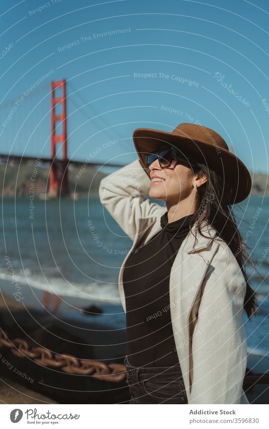 Stilvolle Frau am Wasser stehend mit Brücke im Hintergrund trendy reisen Glück Lächeln jung genießen Tourismus San Francisco Goldenes Tor Kalifornien amerika