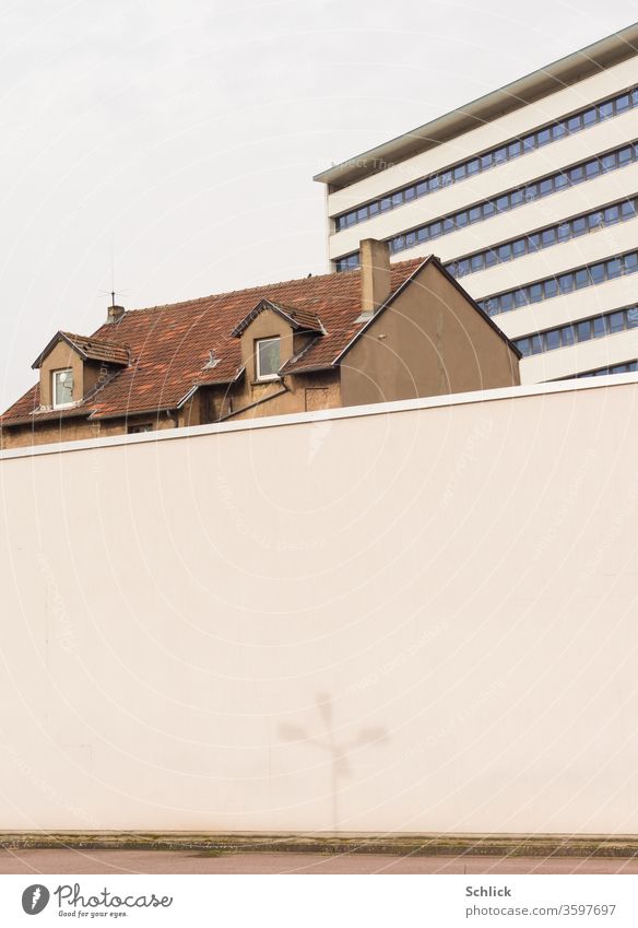 Dach eines alten Hauses zwischen Mauer mit Schatten einer Straßenlampe und neuem Bürogebäude sauber Hochhaus Gegensatz alt und neu Kontrast Architektur Wand