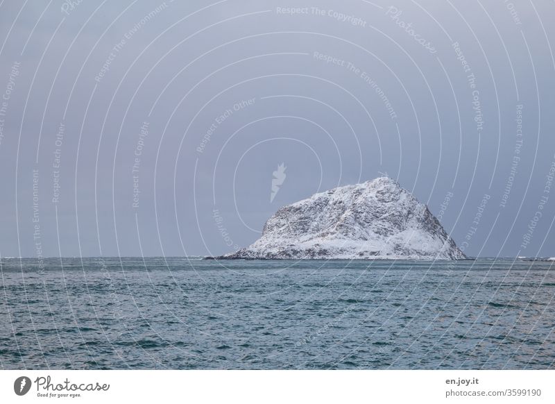 großer Felsen, also eine kleine Insel, im Meer mit Schnee bedeckt, also im Winter Nordmeer Horizont Norwegen Lofoten Skandinavien Haukland Beach schneebedeckt