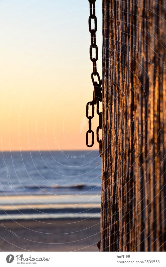 Kette an Holzpfahl am Strand bei Sonnenuntergang Sommerurlaub romantische Stimmung Rost Pfahl Kettenglied Meer Schwache Tiefenschärfe Urlaubsstimmung Erholung