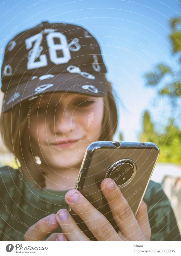 Junge mit Smartphone Verschlussdeckel Kindheit Fotokamera Sommer Blick in die Kamera Kindheitserinnerung Mensch Porträt Farbfoto Freude Tag Gesicht