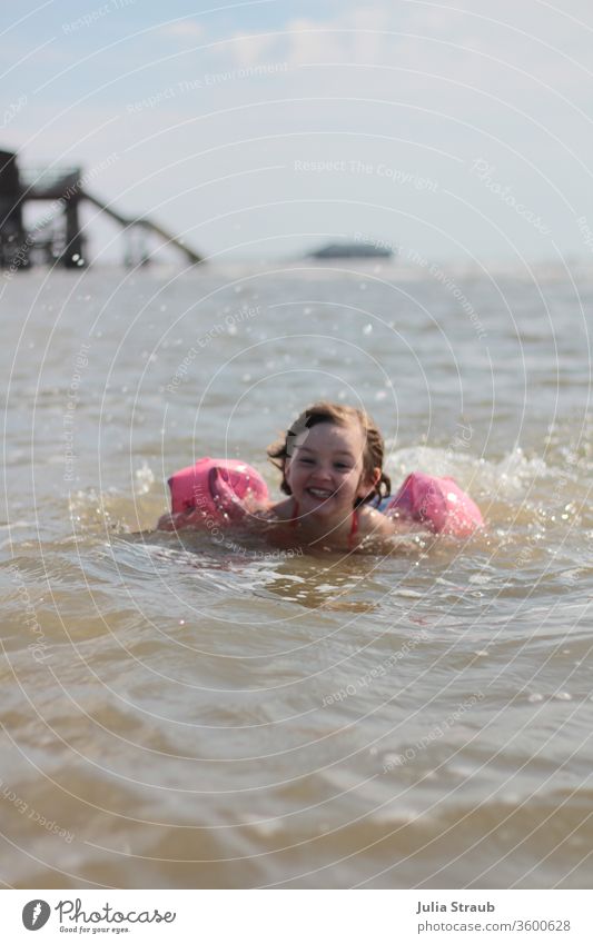 Kleinkind mit Schwimmflügl badet in der Nordsee baden kalt frisch Schwimmen & Baden schwimmflügl Tropfen Wassertropfen Meer Steg Mädchen spaßig Spaß haben