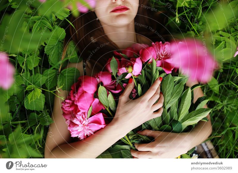 Strauß Pfingstrose. schöne junge Frau liegt unter Pfingstrosen. Feiertage und Veranstaltungen. Valentinstag. Frühlingsblüte. Blumen Porträt Glamour rosa