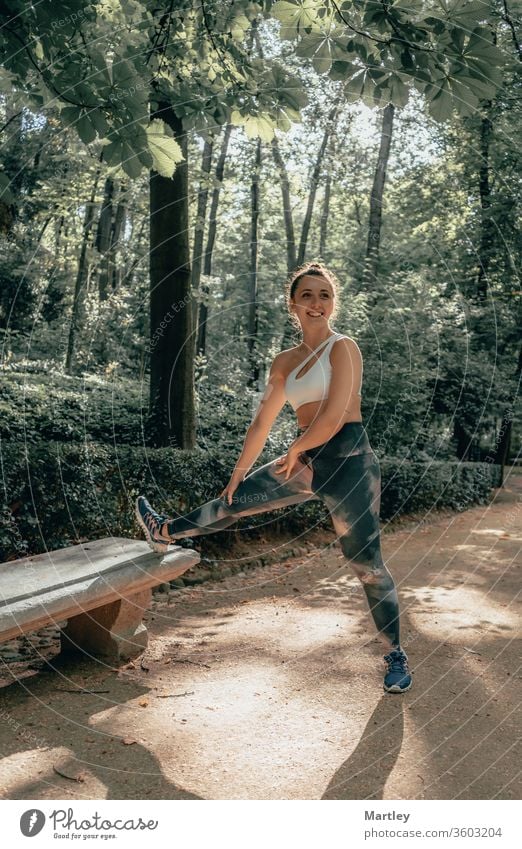 Junge hübsche Sportlerin mit Leggings, die lächelt und im Sommer in einem Wald mit frischer Luft Sport treibt. Frau Natur lächelnde Frau Kind jung im Freien