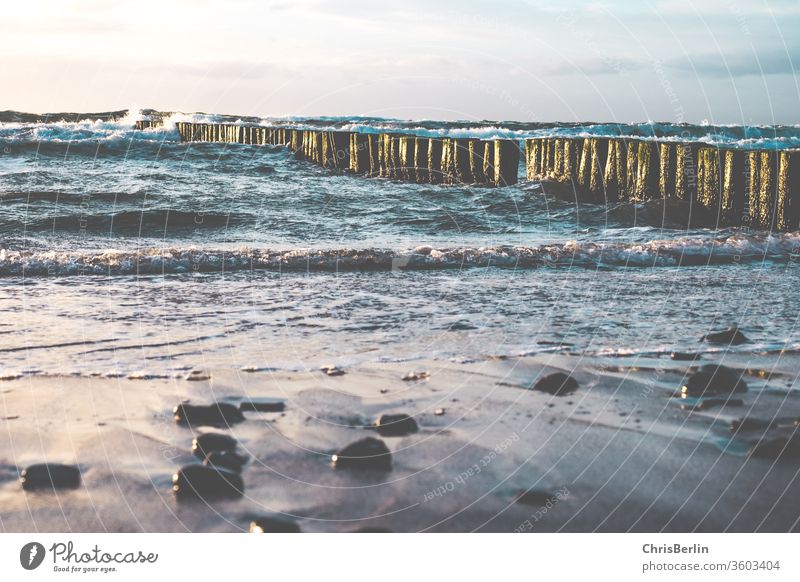 Ostee-Strand mit Wellen und Buhnen Steine Buhnen in der See Sturm Sonnenuntergang Wolken