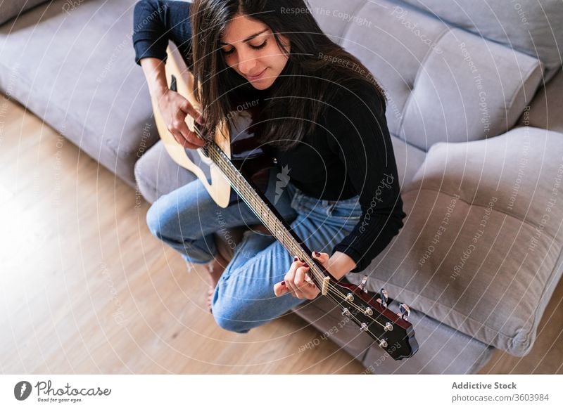 Frau spielt Gitarre und lernt mit Online-Kursen Musik Lifestyle im Innenbereich Lernen Spielen E-Learning Menschen Gitarrenspieler Erwachsener