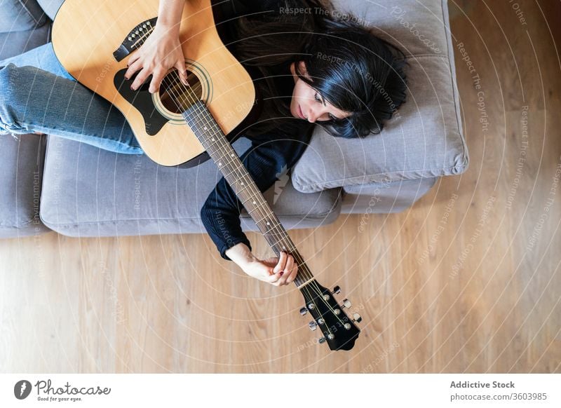 Frau spielt Gitarre und lernt mit Online-Kursen Musik Lifestyle im Innenbereich Lernen Spielen E-Learning Menschen Gitarrenspieler Erwachsener