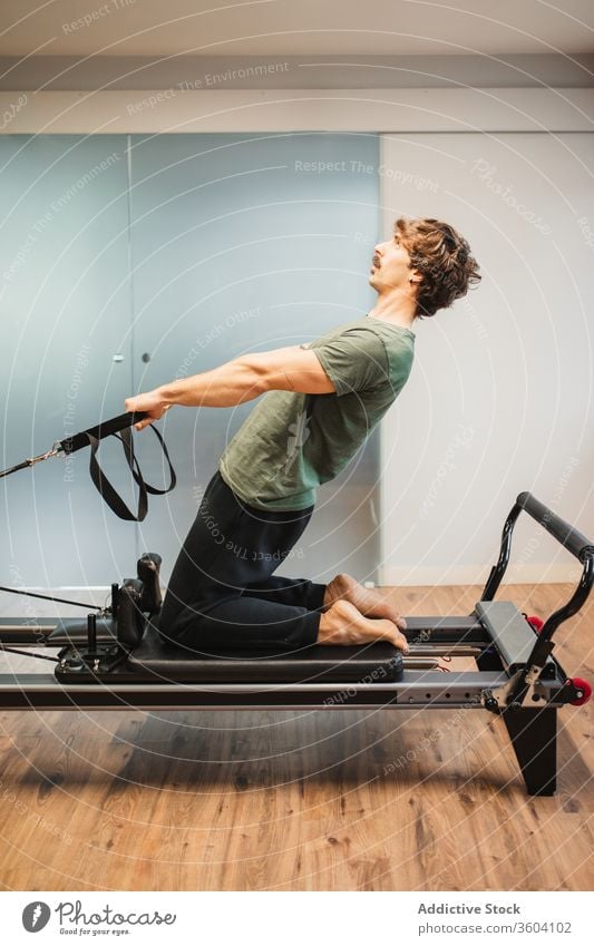 Sportlicher Mann benutzt Pilates-Reformer während des Trainings Dehnung sportlich Sportkleidung widersetzen Band Maschine männlich Sportler Athlet Übung Fitness