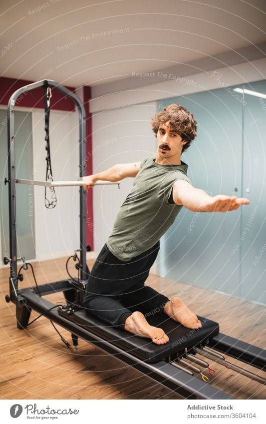 Sportler mit Pilates-Maschine Reformer Übung Training Sportbekleidung Fitnessstudio Gesunder Lebensstil Athlet männlich Gesundheit Kraft Wellness stark physisch