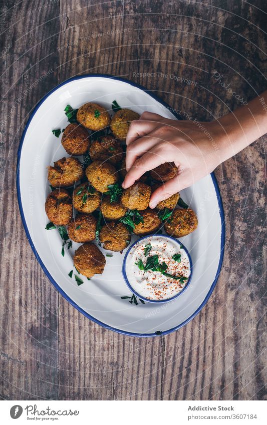 Erntehelfer nimmt Falafel-Ball vom Teller Speise Naher Osten Küche Leckerbissen versuchen Sie Restaurant lecker Portion Kalorie Saucen Bohnenkraut Sahne