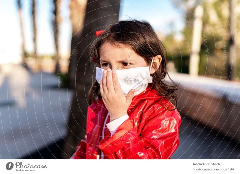 Ethnisches Mädchen mit chirurgischer Maske auf der Straße medizinisch Mundschutz Kind genießen Wochenende Bund 19 behüten ethnisch Kindheit heiter Großstadt