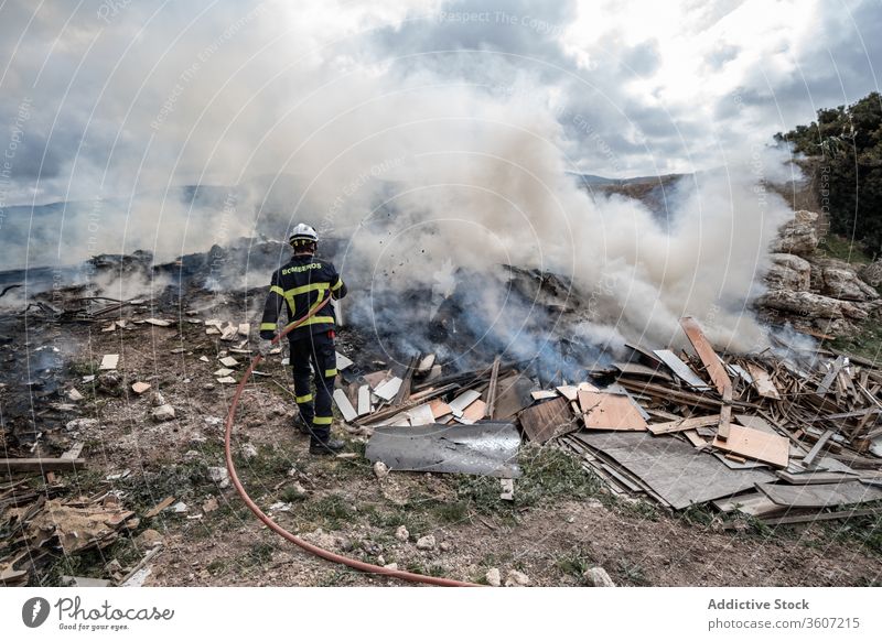 Feuerwehrmann löscht Feuer mit Wasser Mut Schlauch löschen Rauch ausmachen Uniform männlich behüten Arbeit Gerät Job stehen Beruf Schutzhelm Sicherheit Arbeiter