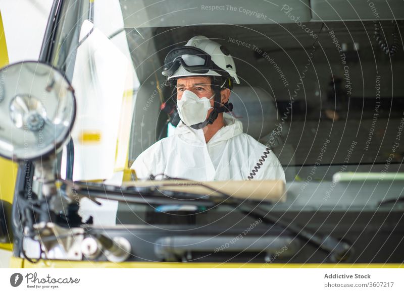 Schwerer Feuerwehrmann in Schutzuniform in einem Auto Mann behüten Uniform Atemschutzgerät männlich Schutzhelm Feuerwehrhaus Tracht medizinisch Mundschutz