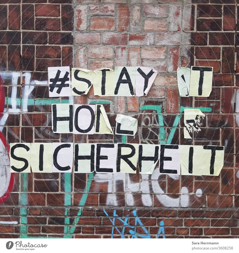 Ein sich ablösender Schriftzug an einer Backsteinmauer Sicherheit stay at home Berlin Corona-Virus Schutz streetart Hashtag