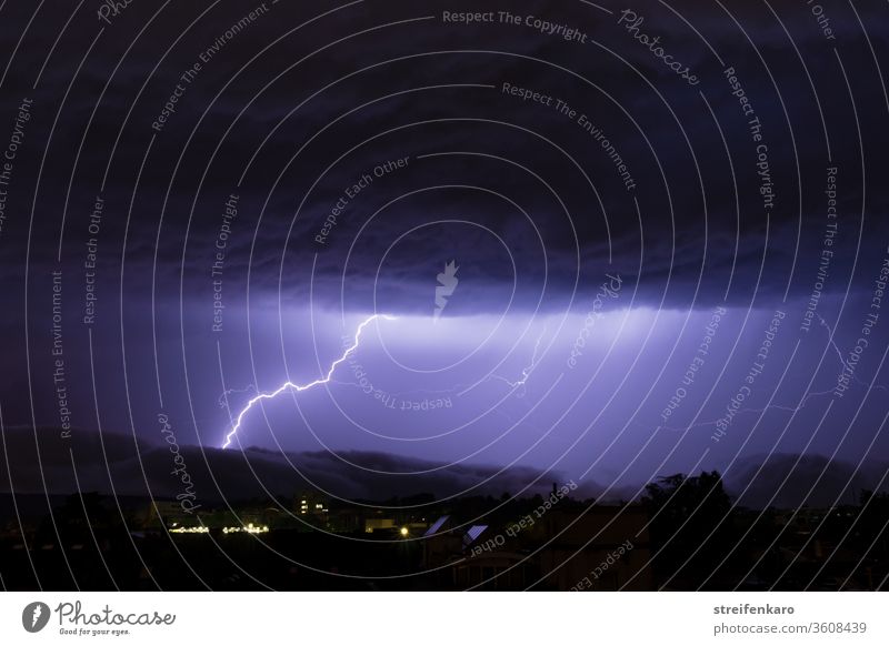 Die mächtigen Wolken über der Stadt rissen auf, so dass das helle Licht der Blitze sichtbar werden konnte Gewitter Nacht Donner Unwetter Außenaufnahme Farbfoto