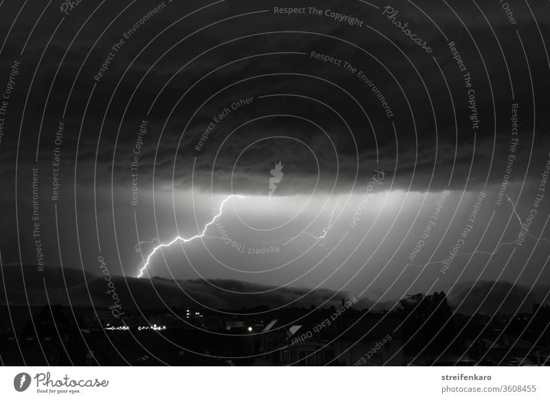 Gewaltige Blitze werden am schwarz-weißen Himmel zwischen den mächtigen Wolkenschichten sichtbar Nacht Gewitter Unwetter Außenaufnahme Donnern Gewitterwolken