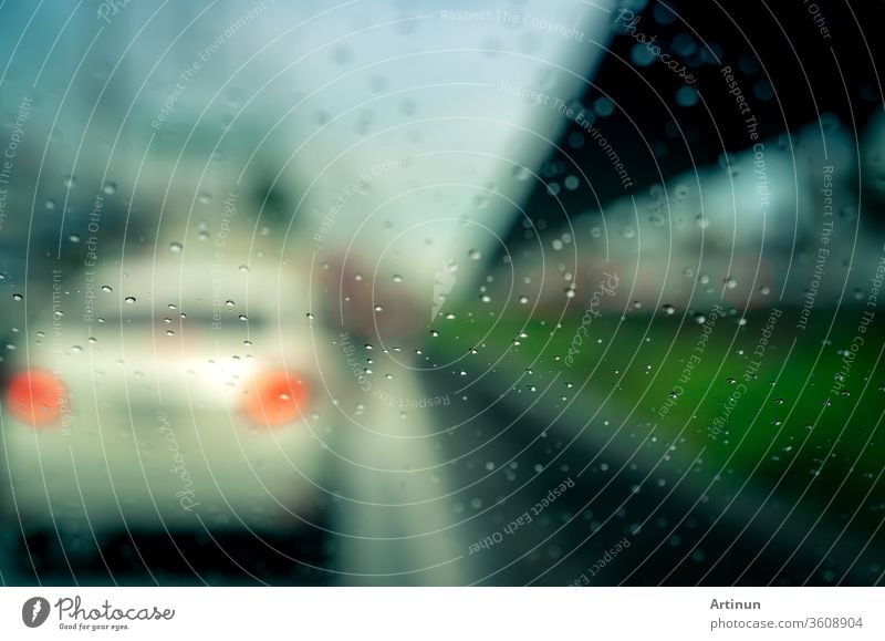 Regentropfen auf der Windschutzscheibe. Auto fährt an einem regnerischen Tag auf Asphaltstrasse. Windschutzscheibe eines Autos mit Regentropfen auf Glaswindschutzscheibe. Verkehrsstau an einem Regentag. Schlechtes Wetter an einem stürmischen Tag. Reisen mit dem Auto.