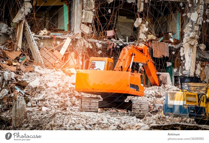 Zerstörte Bauindustrie. Gebäudeabriss durch Explosion. Verlassenes Betongebäude mit Schutt und Schrott. Ruine durch Erdbeben. Beschädigtes oder eingestürztes Gebäude durch Hurrikan-Katastrophe. Tieflöffelbagger.