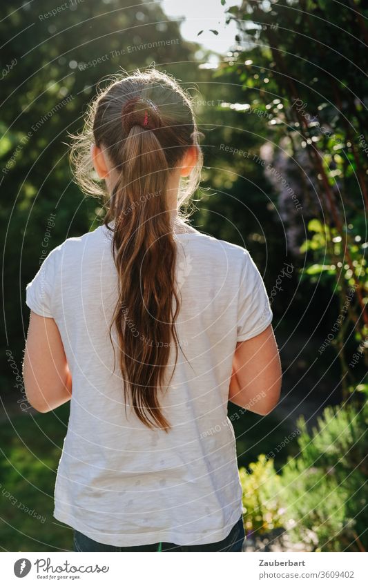 Mädchen mit Pferdeschwanz im güldenen Gegenlicht schaut in den Garten Kind T-Shirt weiß schön hübsch süß schauen Kindheit Sommer sommerlich Natur