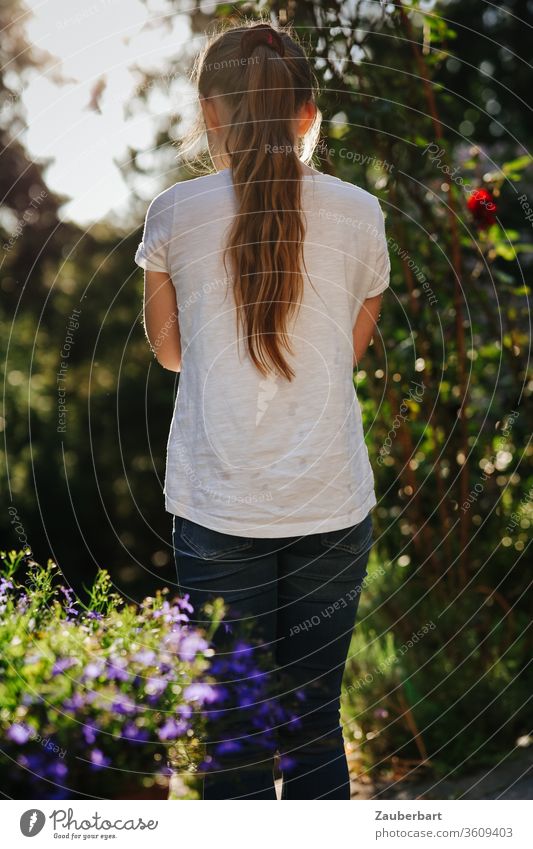 Mädchen mit Pferdeschwanz im Gegenlicht schaut in den Garten Kind T-Shirt weiß schön hübsch süß schauen Kindheit Sommer sommerlich Natur Blumen