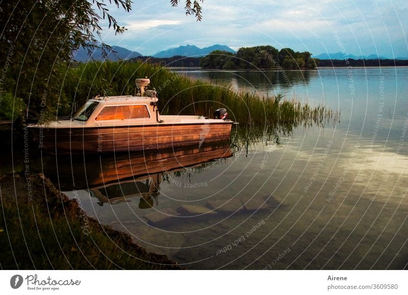 Der schnelle Tag ist hin See Seeufer Abend Boot Abendrot Schiff Insel Berge Idylle Stille Sonnenuntergang Sonnenlicht ruhig Ufer Schilf innehalten Trost