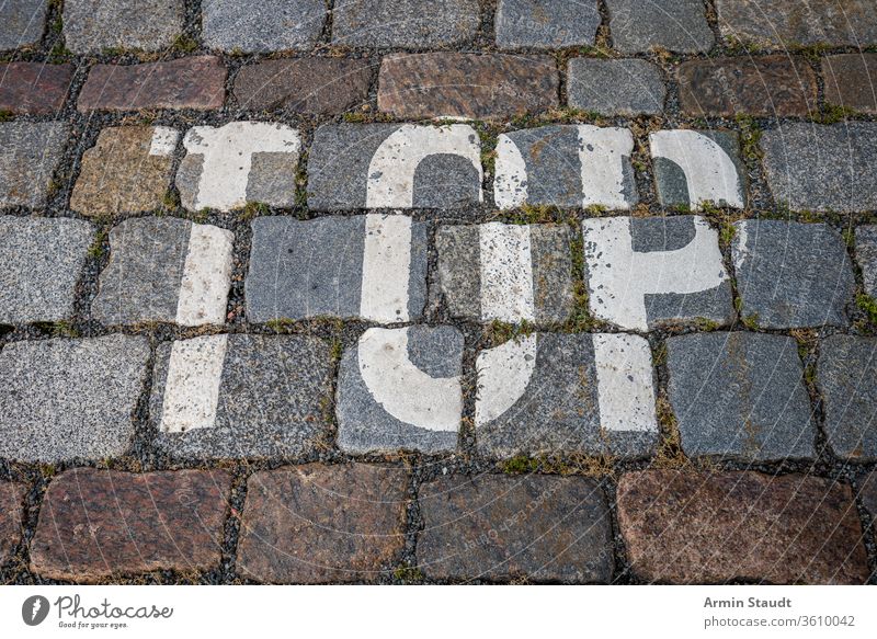 das Wort oben mit weißer Farbe auf Kopfsteinpflaster für Hintergründe abstrakt Alphabet Hintergrund Großstadt Nahaufnahme Design Stock Grunge Andeutung Briefe