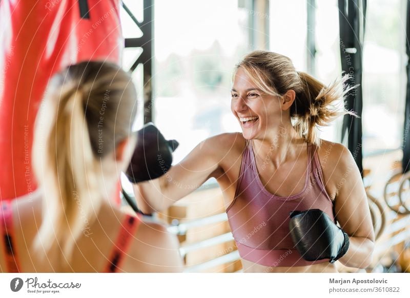 Junge sportliche Frau beim Boxen in der Turnhalle {Lebensstil Sport zäh Stanzen aktiv Konkurrenz blond Motivation Trainerin Gesundheit Handschuhe Ausdauer