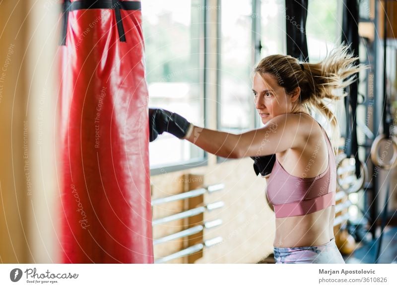 Junge sportliche Frau beim Boxen in der Turnhalle {Lebensstil Sport zäh Stanzen aktiv Konkurrenz blond Motivation Trainerin Gesundheit Handschuhe Ausdauer