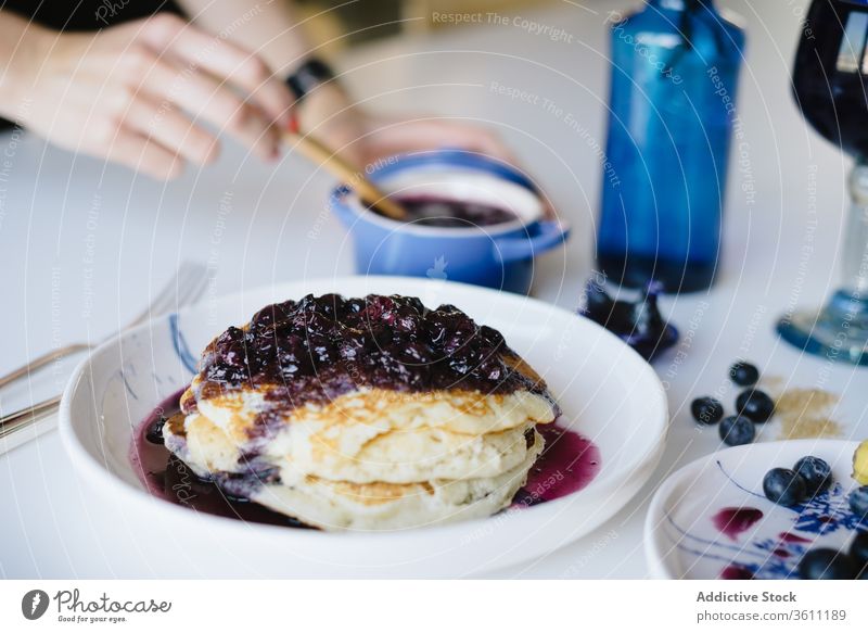 Frau serviert köstlichen Brunch mit Pfannkuchen Frühstück Marmelade Blaubeeren selbstgemacht dienen lecker Lebensmittel Morgen Hand gemütlich Tisch