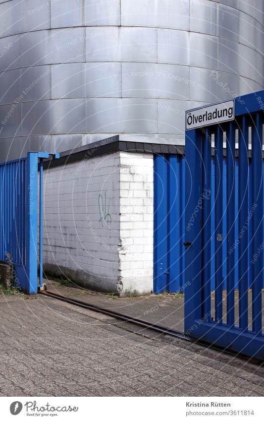 ölverladung - blaues rolltor und stahltank silo stahlsilo zaunanlage toranlage schiebetor gitter rollgitter hochsilo fabrik industrie ölmühle offen geöffnet