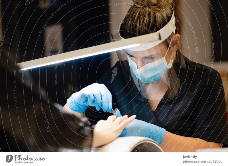 Ästhetiker, der die Maniküre macht, feilt die Nägel mit einer Feile seiner Kundin in einem Schönheitszentrum Aktenordner nageln Nagellack Fingernagel Frau Salon