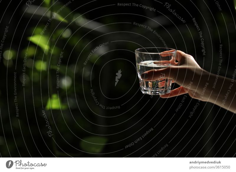 Frau hält ein Glas Wasser auf dunklem Hintergrund. Glas mit reinem Wasser in der Hand. Gesunder Lebensstil. Ökologie Sauberkeit übersichtlich Arme Getränk